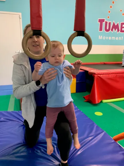 Coach helping a baby reach for the gymnastics rings