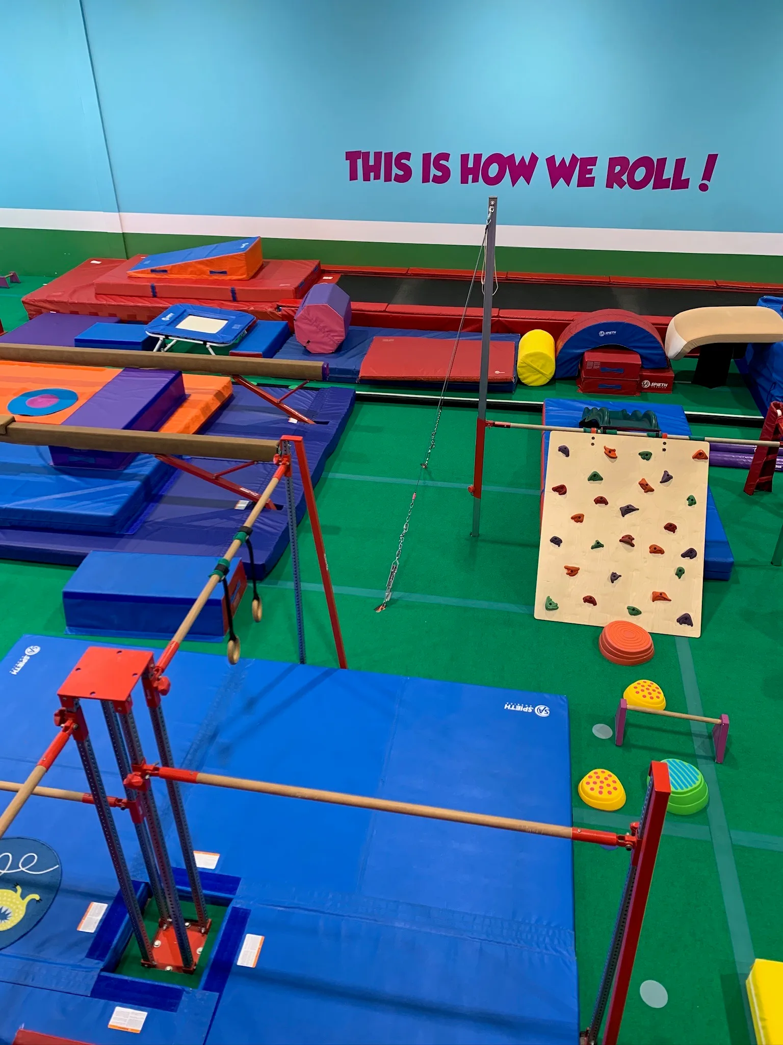 A real TumbleTown gym floor set up with bars, beams, mats and climbing equipment