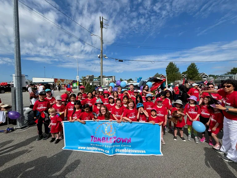 Dozens of kids and coaches in red TumbleTown shirts behind the banner at the Steveston Salmon Festival parade