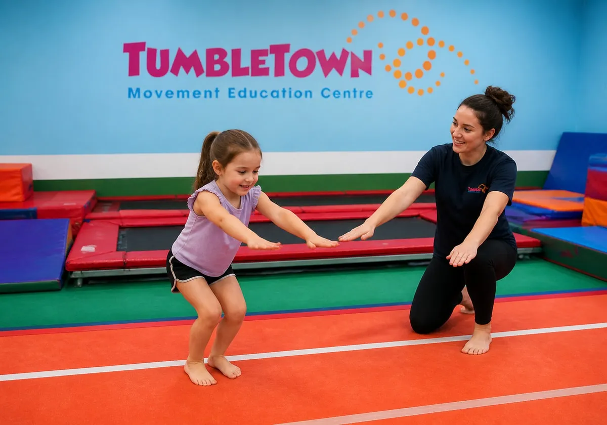 Six-year-old landing a small jump on an orange tumble track with a female instructor